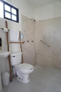 a white bathroom with a toilet and a shower at Casa Calandria in Chicxulub +16 photos