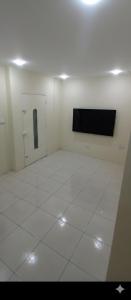 een witte kamer met een televisie en een tegelvloer bij El delfín in Santa Elena