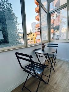 een tafel en een stoel in een kamer met ramen bij Central Tirana Apartments in Tirana