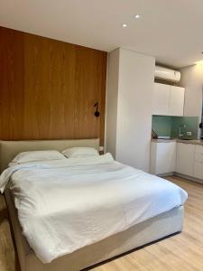 een slaapkamer met een groot wit bed met een houten hoofdeinde bij Central Tirana Apartments in Tirana