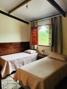 zwei Betten in einem Zimmer mit Fenster in der Unterkunft Reserva do Bosque Hospedaria e Natureza in Ibicoara