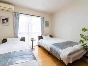 twee bedden in een kamer met een raam bij ゲストハウス海と石 in Takamatsu