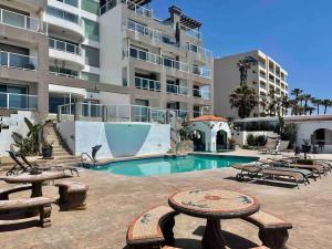 a swimming pool with tables and benches in front of a building at Oceanfront Rosarito Balcony Beach & Amazing Sunsets in Rosarito Beach