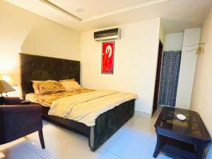 a bedroom with a bed and a chair and a table at Royal Rooms - Misaq-ul-mall in Faisalabad