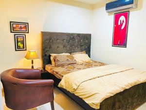 a bedroom with a bed and a chair at Royal Rooms - Misaq-ul-mall in Faisalabad