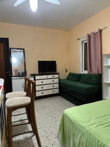 un salon avec un canapé vert et une télévision dans l'établissement Residencial Brila Mar, à Capão da Canoa