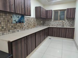 an empty kitchen with wooden cabinets and a window at Royal Rooms - Misaq-ul-mall in Faisalabad