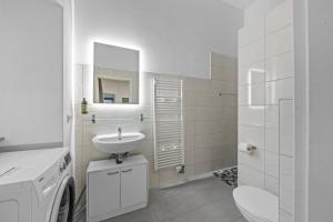 une salle de bains blanche avec un lavabo et un miroir dans l'établissement Apartment Uthman Berlin-Neukölln, à Berlin 6 autres photos