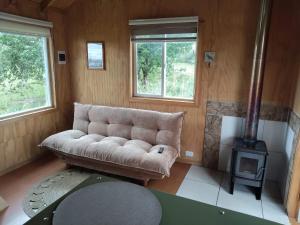a living room with a couch and a stove at La petite cabane de Putemun in Castro