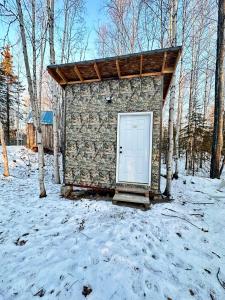 un petit bâtiment avec une porte blanche dans la neige dans l'établissement Bears Den Cabin #3, à Houston