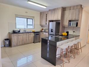 une cuisine avec un comptoir noir et des placards en bois dans l'établissement Valley Rest, à Mbabane