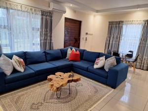 un canapé bleu dans un salon avec une table dans l'établissement Valley Rest, à Mbabane