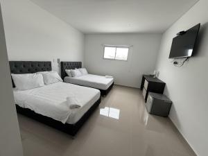 een slaapkamer met twee bedden en een flatscreen-tv bij Tierra Bendecida Hotel Boutique in Villavicencio