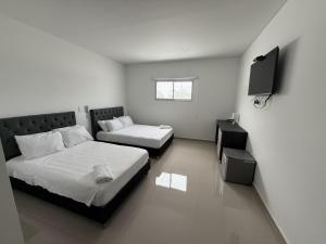 een slaapkamer met twee bedden en een televisie bij Tierra Bendecida Hotel Boutique in Villavicencio