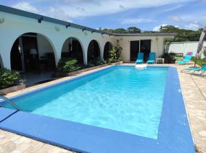 ein Pool mit blauen Stühlen und ein Haus in der Unterkunft mahinas lodge in Mahina + 12 Fotos