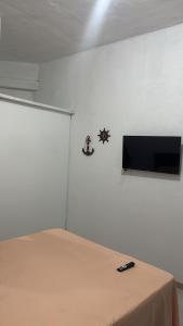 a room with a bed and a tv on a wall at Suíte Macedônia in Arraial do Cabo