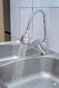 een gootsteen met water uit een kraan bij Villa Bernadette aéroport in Pointe-Noire