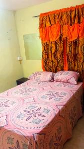 una camera con un letto con una coperta rosa e bianca di Tamaras Inn a Christ Church Altre 5 foto