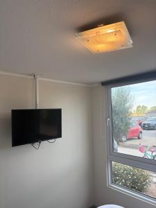 een woonkamer met een flatscreen-tv en een raam bij Comodo y cercano a la playa in Coquimbo
