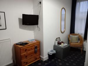 a room with a dresser and a tv on a wall at The Limes Guesthouse Montrose in Montrose