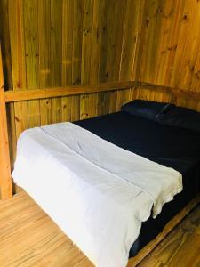 a bed in a room with wooden walls at Casa Praia in Palhoça