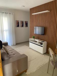 ein Wohnzimmer mit Sofa und Flachbildfernseher in der Unterkunft Apartamento moderno com Piscina e Coworking in Parnamirim