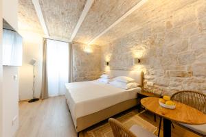a bedroom with a bed and a stone wall at Porto Nativo Split in Split