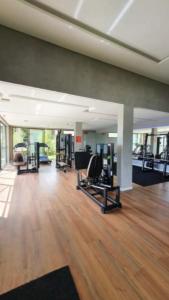 ein Fitnessraum mit Holzböden und ein großes Zimmer mit Maschinen in der Unterkunft Apartamento moderno com Piscina e Coworking in Parnamirim