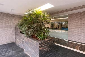 a lobby with a large plant in a brick wall at Apto elegante no Catolé 33 in Campina Grande