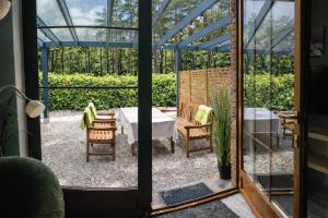 a glass house with a patio with a table and chairs at Domki apartamenty Nasza Chata - 4 minuty od plaży in Pobierowo