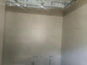a bathroom with a large white tile wall at The Ambience in Maseru