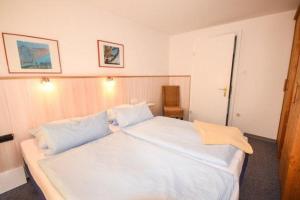 a bedroom with a large white bed with blue pillows at Haus Seerose, Nr 8 in Baltrum
