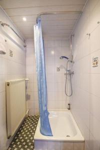 a bathroom with a tub with a blue shower curtain at Haus Seerose, Nr 8 in Baltrum +3 photos