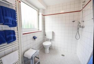 e bagno con servizi igienici, doccia e asciugamani blu. di Haus Seerose, Nr 8 a Baltrum