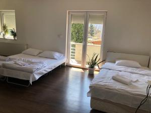 two beds in a room with a large window at NOVA residence in Sarajevo