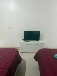 a room with two beds and a television on a cabinet at Escobar Centro II in Belén de Escobar
