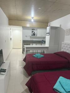 a bedroom with two beds and a table and a kitchen at Escobar Centro II in Belén de Escobar
