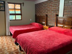 een kamer met 2 bedden en een bakstenen muur bij Cabañas las Gemelas in Areponapuchi