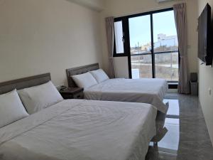 a hotel room with two beds and a window at Starry Night Travel Homestay in Magong