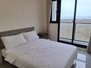 een slaapkamer met een wit bed en een groot raam bij 星輝漫旅 in Magong