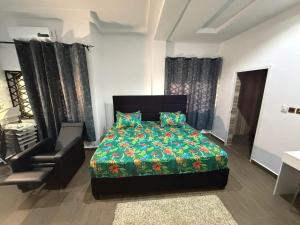 a bedroom with a bed and a chair in it at Miky Hillside Lodge in Sunyani