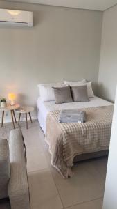 a white bedroom with a bed and a table at Loft Centralíssimo com Garagem in Pelotas