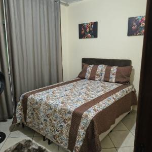 een slaapkamer met een bed met een dekbed en kussens bij Casa Temporada Prado-BA in Prado