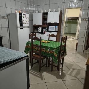 een keuken met een tafel, stoelen en een koelkast bij Casa Temporada Prado-BA in Prado