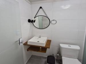 a white bathroom with a sink and a mirror at Pousada a 500 metros do Pico Malwee in Jaraguá do Sul