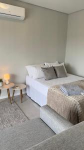 a white bedroom with a bed and a table at Loft Central com garagem in Pelotas