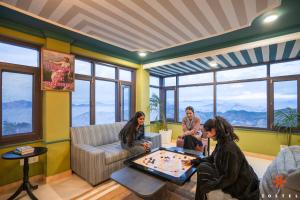 a group of people playing chess in a room with windows at Zostel Kufri in Kūfrī