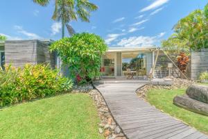 a home with a wooden walkway in the yard at ArtHOUSE Beachfront Accommodation in Emerald Beach