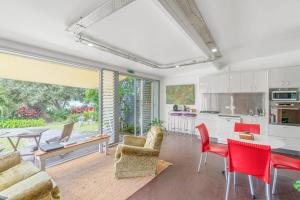 a kitchen and living room with red chairs and a table at ArtHOUSE Beachfront Accommodation in Emerald Beach +66 photos
