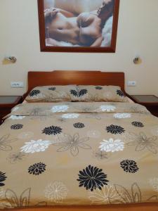 a bed with a comforter with flowers on it at Hotel Village in Stari Banovci